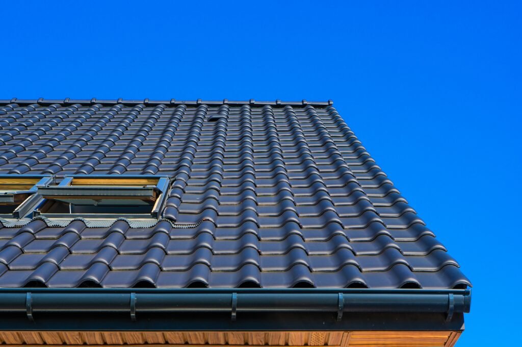 vertical low angle closeup shot of the black roof of a building with a blue background